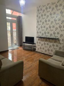 a living room with a couch and a tv at 3/4 Bedroom House in Manchester