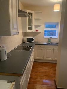 a kitchen with white cabinets and a black counter top at 3/4 Bedroom House in Manchester