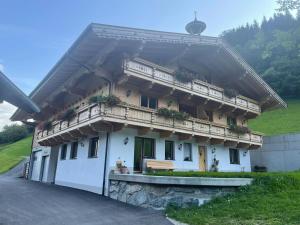a white house with a balcony on a hill at Alpen-Appartement Auerhof in Volders