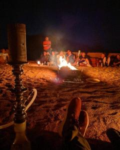 a group of people sitting around a fire at night at Golden Sands Camp in Wadi Rum