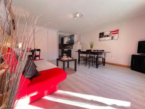 a living room with a red couch and a dining room at T2 ensoleillé. Terrasse et vaste jardin commun in Cauterets
