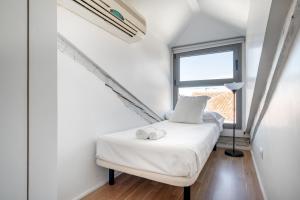 - une petite chambre avec un lit blanc et une fenêtre dans l'établissement Minty Stay - Imperial 2BD, à Madrid