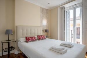a white bed in a room with a large window at Minty Stay - Plaza Mayor 3 BD in Madrid