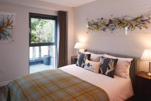 a bedroom with a bed with pillows and a window at Riverside West End Apartment in Glasgow
