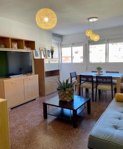 ein Wohnzimmer mit einem Sofa, einem TV und einem Tisch in der Unterkunft UIM Mediterraneo Diagonal 16 Wfi in Puerto de Sagunto
