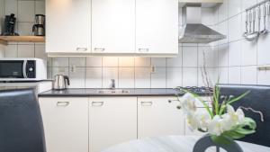 uma cozinha com armários brancos e uma mesa com flores brancas em Zeelucht Texel em De Koog