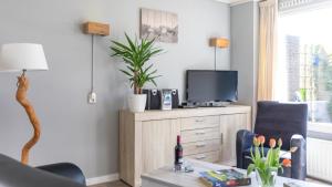 a living room with a tv on a dresser with a table at Zeelucht Texel in De Koog