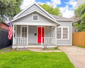 uma casa branca com uma porta vermelha e uma bandeira em Artsy Heights House: Walk To Food-Bars-Shops-Trails, Kids & Pet Friendly em Houston