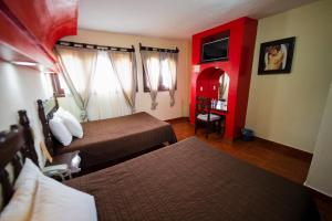 Habitación de hotel con 2 camas y pared roja en Hotel D’Monica en San Cristóbal de Las Casas