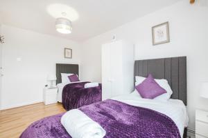 two beds in a room with purple sheets at Spacious 3-Bedroom House near ExCeL Free Parking E16 in London