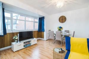 a living room with a television and a table with chairs at Spacious 3-Bedroom House near ExCeL Free Parking E16 in London