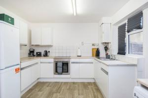 a white kitchen with white appliances and white cabinets at Spacious 3-Bedroom House near ExCeL Free Parking E16 in London