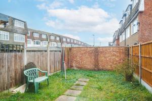 a green bench sitting in front of a fence at Spacious 3-Bedroom House near ExCeL Free Parking E16 in London