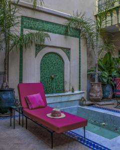 une chaise rose assise devant une fontaine dans l'établissement Riad Dar Habiba by Garden Wonders, à Marrakech