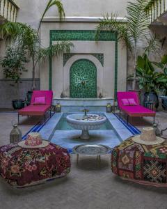 a courtyard with two pink chairs and a fountain at Riad Dar Habiba by Garden Wonders in Marrakech