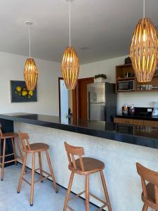 a kitchen with a counter with chairs and lights at Casa Beija Flor in Porto Seguro