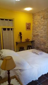 a bedroom with a white bed and a stone wall at El Condado Casa Rural in Fuentes de Oñoro