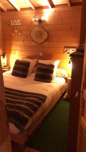 La Cabane à l'Orée des Bornes في Évires: سرير في غرفة خشبية عليها وسادتين