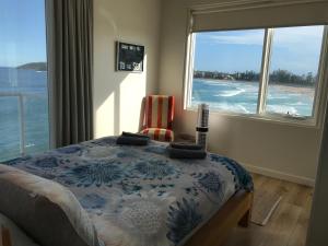 a bedroom with a bed and a view of the ocean at Manly Waterfront Beach Stay in Queenscliff