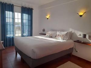 レゲンゴス・デ・モンサラーシュにあるTerras de Monsarazのベッドルーム(青いカーテン付きの白い大型ベッド1台付)