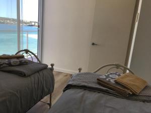 two beds in a room with a view of the ocean at Manly Waterfront Beach Stay in Queenscliff