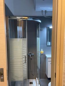 La salle de bains est pourvue d'une douche avec une porte en verre. dans l'établissement AVR Airport Deluxe Suites 4, à Markopoulon