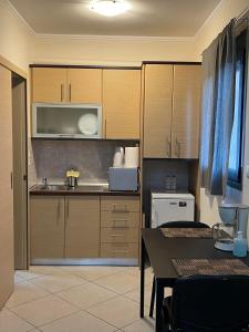 uma cozinha com armários de madeira, uma mesa e um micro-ondas em AVR Airport Deluxe Suites 4 em Markopoulo Mesogaias