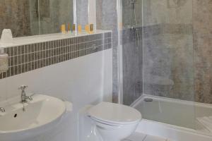 a bathroom with a toilet and a sink and a shower at Old Hunstanton Le Strange Arms Hotel in Hunstanton