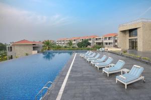 a row of lounge chairs next to a swimming pool at Radisson Blu Resort Visakhapatnam in Visakhapatnam