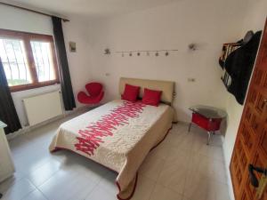 a bedroom with a bed with red pillows and a red chair at villa Anastasia in Cumbre del Sol