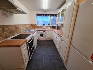 a kitchen with a sink and a refrigerator at 6 bed, sleeps 8, 1 Mile from New Cross Hospital, 10 mins from M6 Jct 10 & M54 Jct 1 in Fallings Park