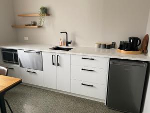 a white kitchen with a sink and a stove at Northcoast Getaway in Mangawhai +6 photos