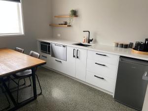 a kitchen with white cabinets and a table and a sink at Northcoast Getaway in Mangawhai