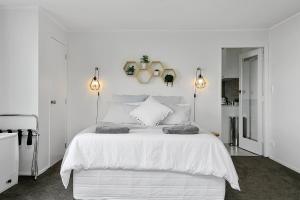 a white bedroom with a large white bed with two lights at Acacia Bay in Taupo