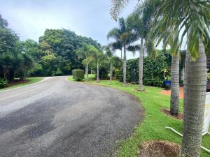 uma entrada com palmeiras ao lado de uma casa em Tolga Caravan Park em Tolga