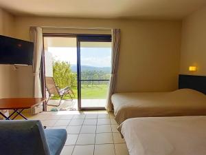um quarto de hotel com duas camas e uma porta de vidro deslizante em terrace IRIOMOTEJIMA CONDOMINIUM em Iriomote