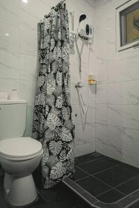 a bathroom with a toilet and a shower curtain at OKEANOS HOTEL in Moalboal