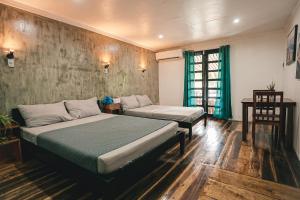 1 dormitorio con 2 camas, mesa y ventana en OKEANOS HOTEL en Moalboal