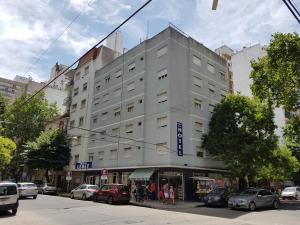 un gran edificio blanco en una calle de la ciudad con coches en Hotel Lebet en Mar del Plata