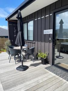 a patio with a table and an umbrella on a deck at Northcoast Getaway in Mangawhai