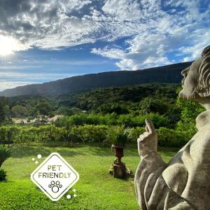 a statue sitting in the grass with a sign that says get friendly at Segredo da Serra Guest House in Tiradentes