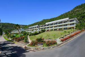 a large apartment building with a garden in front of a mountain at Lagoon Beachfront Lodge 202 on Hamilton Island by HamoRent in Hamilton Island