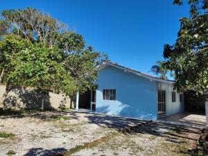 a home with a white garage and trees at Casa Brisa do Mar Itapoá conforto à uma quadra da praia in Itapoa