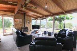 uma sala de estar com sofás e uma televisão e janelas em Gracedale Hills Homestead em Healesville