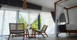 Schlafzimmer mit 2 Stühlen, einem Bett und Fenstern in der Unterkunft Eagle Bay Retreat Borneo Beach Villas Beach Front in Kumbatang