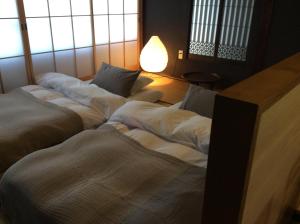 three beds lined up in a room with a lamp at Kitahama Sumiyoshi in Takamatsu
