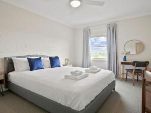 a bedroom with a large white bed with blue pillows at Finchs Nest in Moss Vale