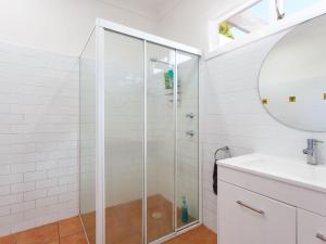 une salle de bain blanche avec une douche et un lavabo dans l'établissement Myall River Cottage, à Tea Gardens 14 autres photos