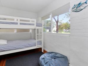 a bedroom with two bunk beds and a window at Myall River Cottage in Tea Gardens