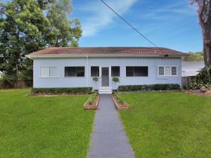 une maison blanche avec un chemin dans la cour dans l'établissement Myall River Cottage, à Tea Gardens